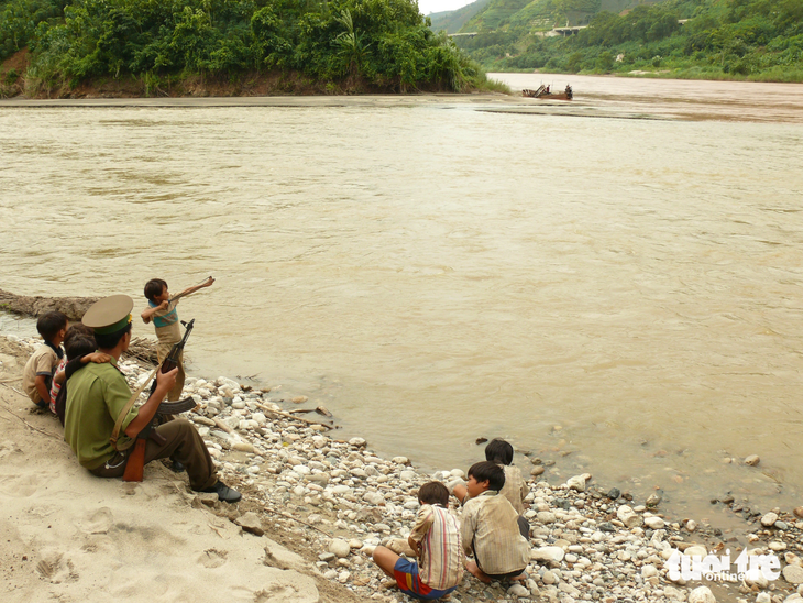 Trung úy Trần Văn Duẩn vui vẻ cùng đám trẻ chơi trò bắn ná ở nơi sông Hồng chảy vào đất Việt  - Ảnh QUỐC VIỆT