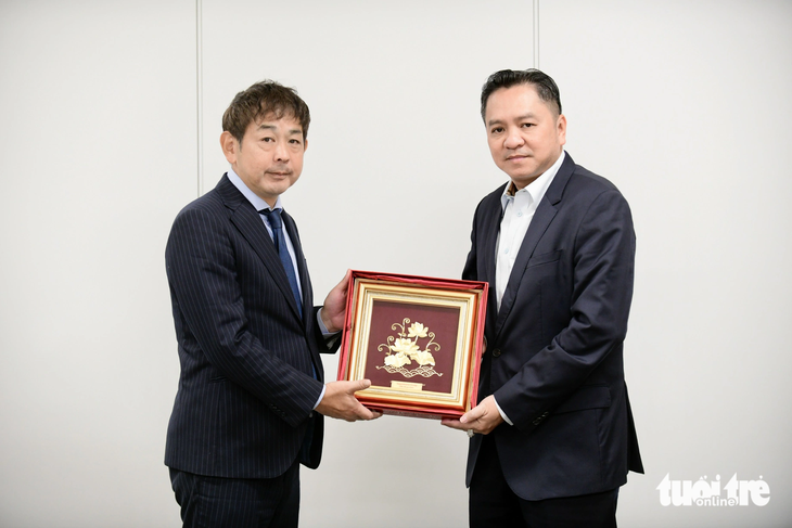 Ông Phạm Huy Bình - chủ tịch hội đồng thành viên Saigontourist Group (phải) - tặng quà lưu niệm là bức tranh sen vàng cho đại diện báo Mainichi - ông Yoshiro Tanaka - Ảnh: QUANG ĐỊNH