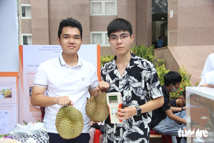Bạn Đinh Trung Đức, sinh viên sư phạm vật lý K21 Trường ĐH Tây Nguyên (phải), và chiếc máy kiểm tra độ chín sầu riêng - Ảnh: MINH PHƯƠNG
