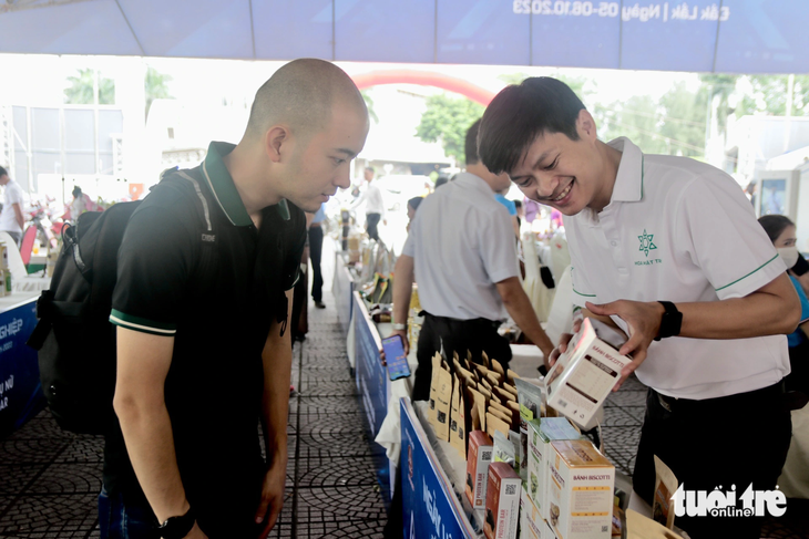 Anh Đặng Đình Luân, á quân cuộc thi Dự án khởi nghiệp thanh niên nông thôn tỉnh Đắk Lắk năm 2022 (phải), giới thiệu đến khách hàng về dự án chăn nuôi dế mèn và các sản phẩn từ dế - Ảnh: THẾ THẾ