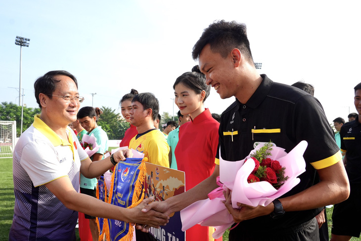 Ông Nguyễn Hoàng Nguyên - phó tổng biên tập Báo Tuổi Trẻ - trao cờ lưu niệm cho đại diện tổ trọng tài và các đội bóng - ẢNH: HỮU HẠNH