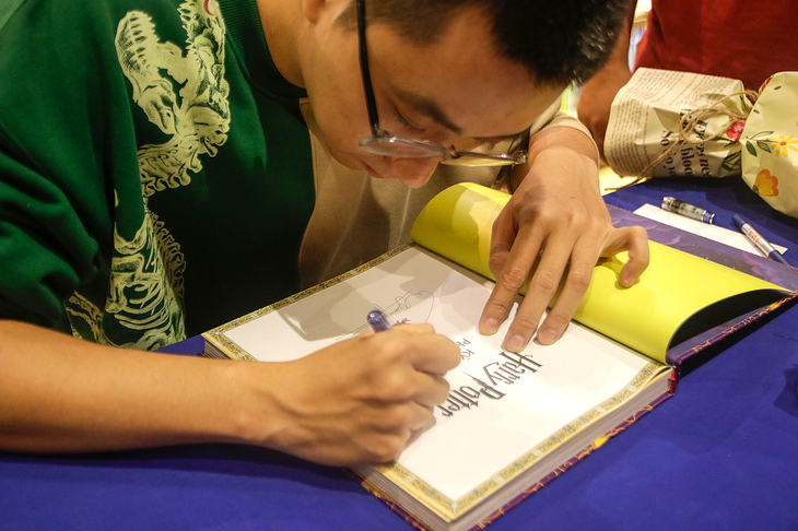 Họa sĩ Phạm Quang Phúc ký tặng sách Harry Potter - Kỳ thư phù thủy cho độc giả - Ảnh: HỒ LAM