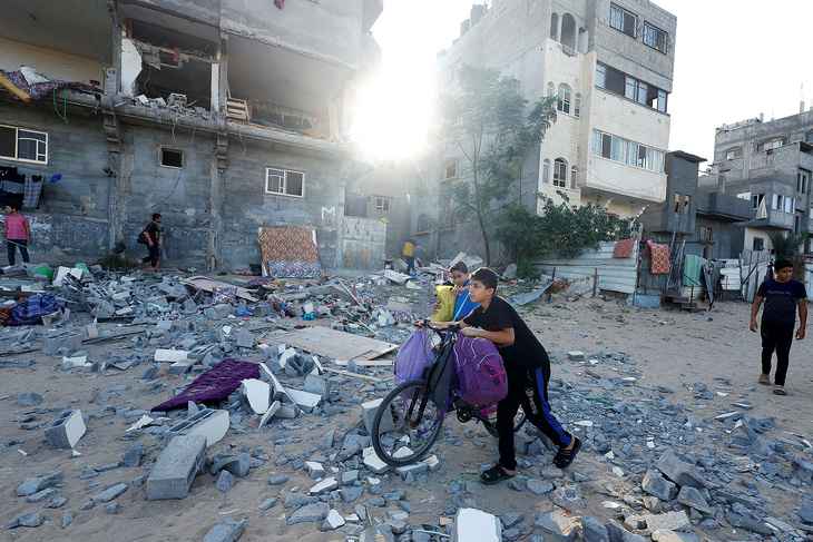 Các em trai người Palestine phía trước dãy nhà bị phá hủy trong đợt không kích của Israel tại vùng Khan Younis ở phía nam Dải Gaza hôm 30-10 - Ảnh: REUTERS