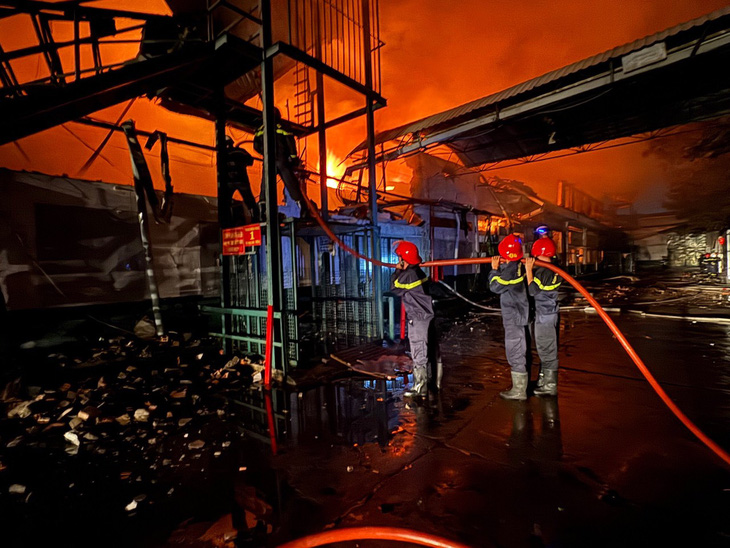 Đến 21h15, lực lượng PCCC vẫn đang nỗ lực dập tắt đám cháy. Ngọn lửa đỏ rực bao trùm nhà xưởng, các bức tường quanh nhà xưởng đổ sập do sức nóng - Ảnh: PC07