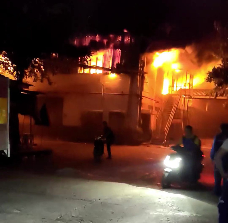 Người dân xung quanh nhà xưởng vội chạy xe máy ra khỏi khu vực cháy, tránh thiệt hại thêm tài sản - Ảnh: TÂM LÊ