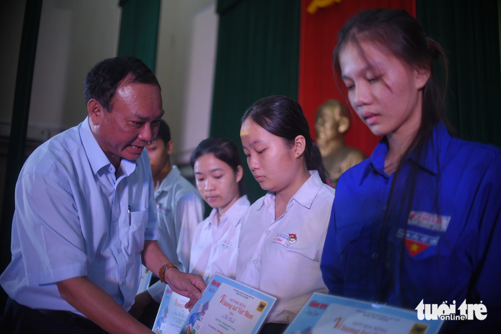 Ông Huỳnh Huyện - phó trưởng Ban Tuyên giáo Tỉnh ủy Bình Định - trao học bổng cho các bạn học sinh - Ảnh: LÂM THIÊN