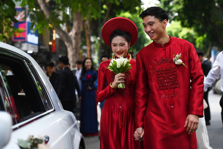 Văn Hậu và Hải My thay bộ áo dài đỏ bước ra xe về Thái Bình để tiếp tục lễ cưới ở quê nhà - Ảnh: HÀ AN
