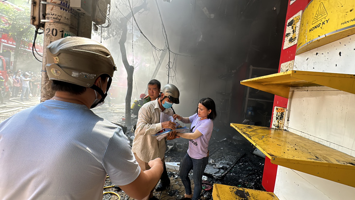 Người dân cố gắng thu dọn giấy tờ, đơn hàng trong cửa tiệm đã bị cháy lan - Ảnh: TRUNG TÂN