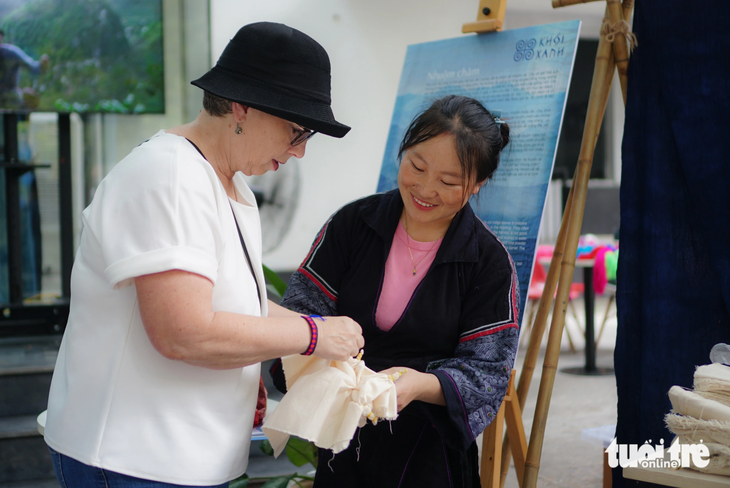 Sùng Thị Lan hướng dẫn du khách nước ngoài nhuộm vải với nước chàm được mang từ Sa Pa xuống - Ảnh: NGUYỄN HIỀN