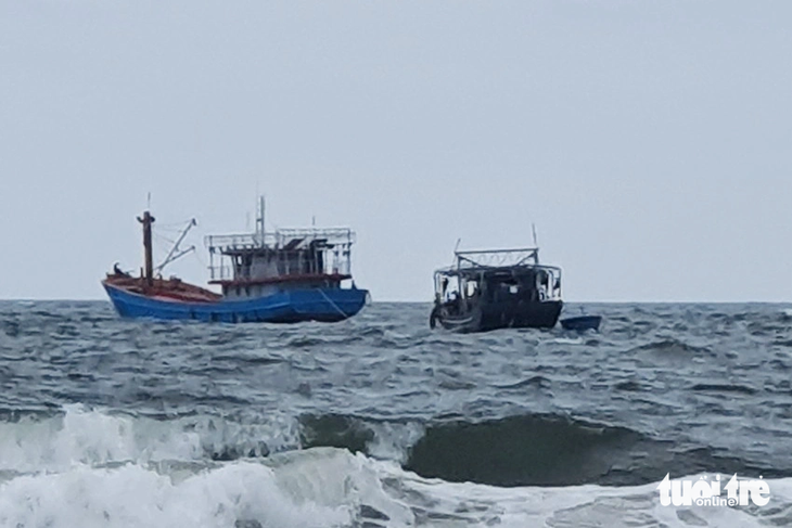 Tàu sắt (phải) trôi dạt, đang được lai dắt vào bờ - Ảnh: QUANG HÀ