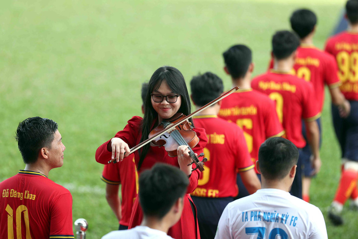 Cầu thủ phong trào thích thú khi bước ra sân trong sự chào đón của nhạc sĩ violin - Ảnh: N.K.