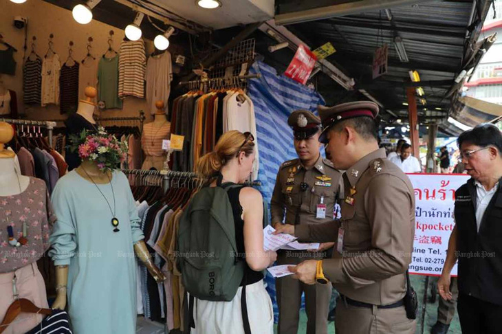 Cảnh sát Thái Lan phát tờ rơi cảnh báo an toàn cho du khách ở Bangkok - Ảnh: Bangkok Post