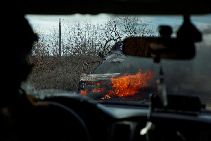 Quân nhân Ukraine di chuyển băng qua một chiếc ô tô đang bốc cháy (do bị máy bay không người lái tấn công) bên ngoài thành phố Avdiivka, Donetsk, đông Ukraine hôm 8-11 - Ảnh: REUTERS