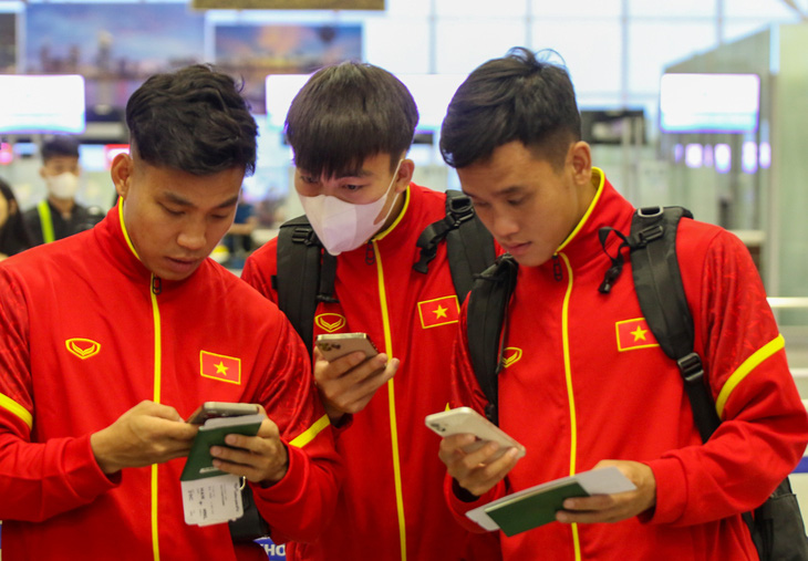 Từ trái qua: Vũ Văn Thanh, Hoàng Văn Toản và Võ Minh Trọng xem thông tin trong lúc làm thủ tục tại sân bay Nội Bài sáng 13-11 - Ảnh: VFF