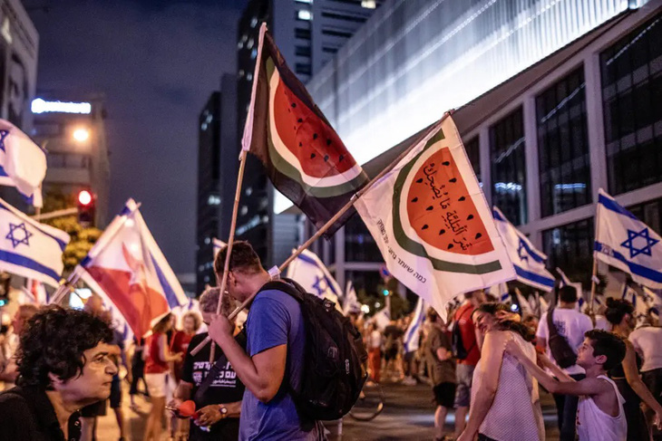 Người biểu tình mang lá cờ dưa hấu thay cho lá cờ Palestine trong một cuộc tuần hành ở Tel Aviv (Israel) - Ảnh: BUSINESS INSIDER