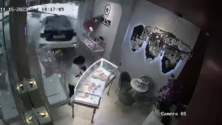 Khoảnh khắc chiếc xe ô tô do nữ tài xế điều khiển lùi tông trúng cửa hàng bán đồ trang sức và làm một bảo vệ tại đây bị thương nặng - Ảnh: Cắt từ video