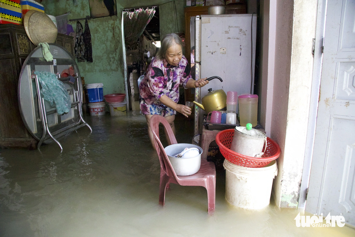 Bà Nguyễn Thị Gái trở về dọn dẹp nhà sau một đêm tránh lũ ở nhà hàng xóm - Ảnh: HOÀNG TÁO
