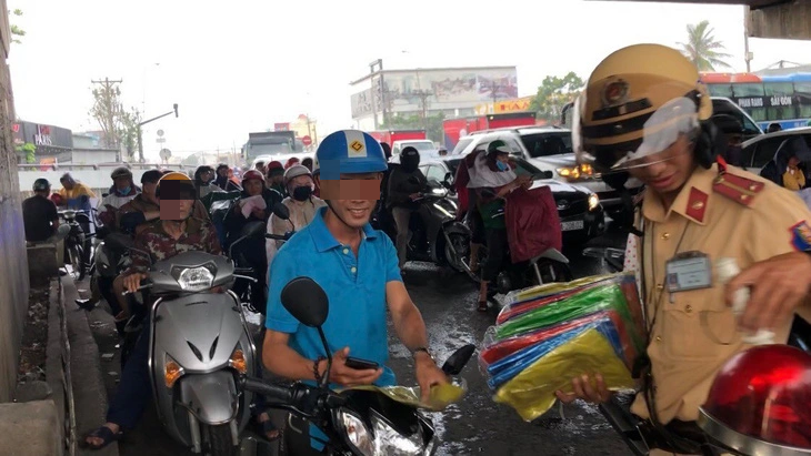 Trú mưa dưới gầm cầu cũng là hiện tượng diễn ra phổ biến ở Việt Nam. Trong ảnh: Cảnh sát giao thông phát áo mưa và giải tán xe máy trú mưa dưới gầm cầu gây cản trở giao thông - Ảnh: M.V.