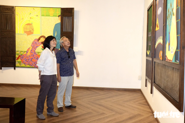 Hai cha con họa sĩ Nguyễn Ngọc Đan xem loạt tranh triển lãm - Ảnh: HỮU HẠNH