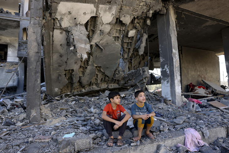 Trẻ em Gaza ngồi giữa đống đổ nát sau cuộc không kích của Israel hôm 10-11 - Ảnh: AFP