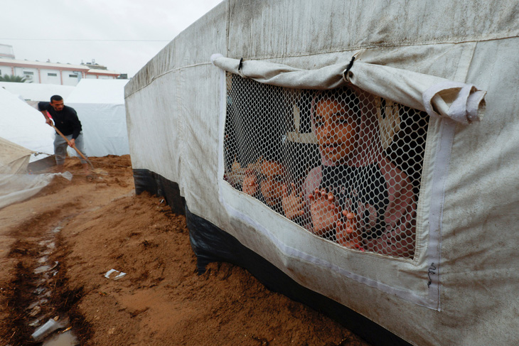 Những đứa trẻ Palestine nhìn ra ngoài lều sau trận mưa ở Khan Younis, phía nam Dải Gaza, giữa xung đột Israel - Hamas, ngày 19-11 - Ảnh: REUTERS