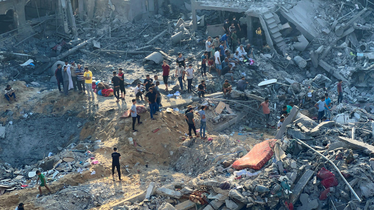 Người Palestine ở trại tị nạn Jabalia tụ tập quanh một hố bom do không kích ngày 31-10 của Israel - Ảnh: REUTERS