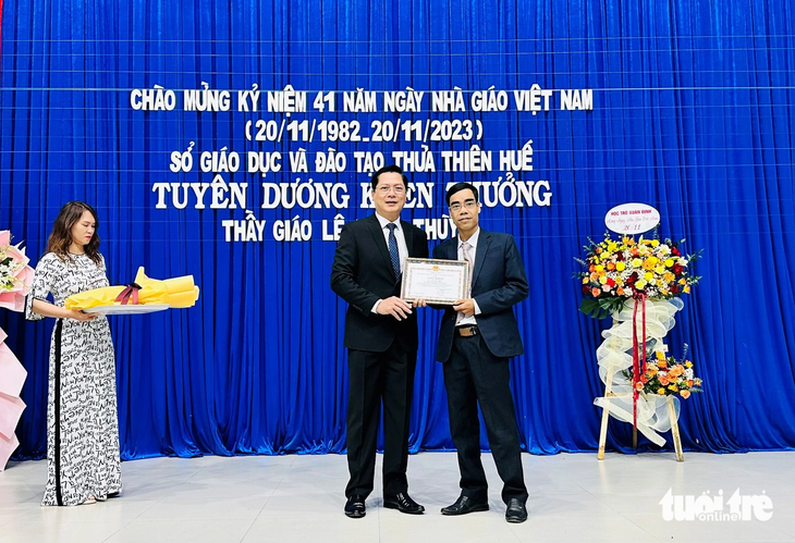 Ông Đoàn Minh Thắng (trái, phó giám đốc Sở Giáo dục và Đào tạo Thừa Thiên Huế) trao bằng khen cho thầy Lê Ngọc Thùy vì hành động dũng cảm cứu người bị nước lũ cuốn trôi - Ảnh: HUỲNH TRƯỜNG THÂN