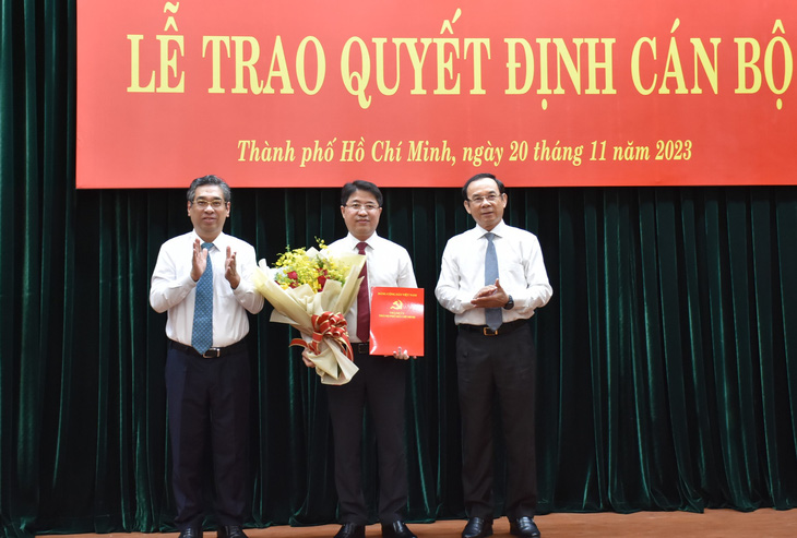 Bí thư Nguyễn Văn Nên (bìa phải) và Phó bí thư Nguyễn Phước Lộc trao quyết định và hoa chúc mừng cho Chánh văn phòng Thành ủy Phạm Hồng Sơn - Ảnh: L.N