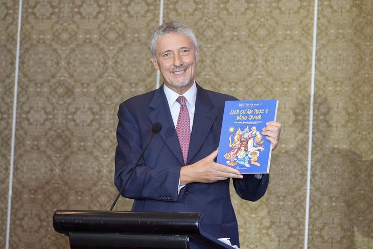 Tổng lãnh sự Ý tại TP.HCM, ông Enrico Padula, giới thiệu cuốn sách về lịch sử ẩm thực Ý bằng tranh - Ảnh: HỮU HẠNH