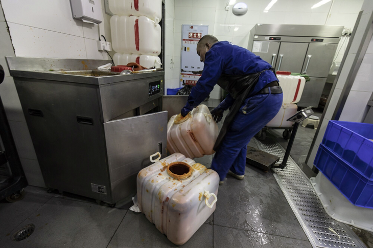 Một công nhân đang lấy thùng đựng dầu tại một quán lẩu ở thành phố Thành Đô, Trung Quốc - Ảnh: BLOOMBERG