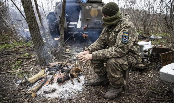 Một người lính Ukraine cố gắng giữ ấm trên tiền tuyến ở tỉnh Donetsk - Ảnh: ANADOLU AGENCY