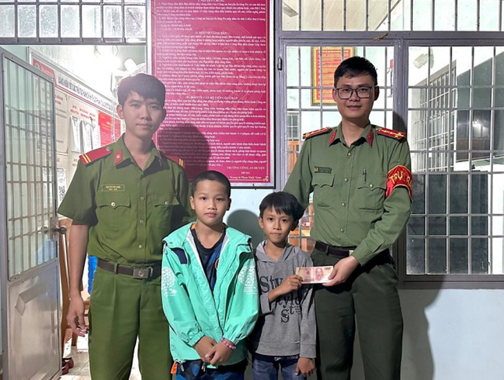 Em Nguyễn Hoàng Anh (9 tuổi) và Nguyễn Sinh Phúc (10 tuổi) nhặt được xấp tiền và tới công an để nhờ tìm người đánh rơi - Ảnh: Công an cung cấp