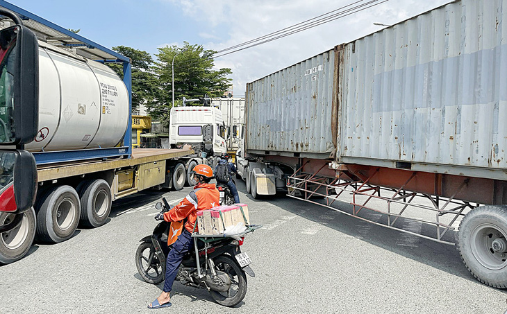 Xe máy bị lọt thỏm giữa nhiều xe container tại vòng xoay Phú Hữu hướng vào đường Nguyễn Duy Trinh dẫn vào cảng Phú Hữu - Ảnh: LÊ PHAN