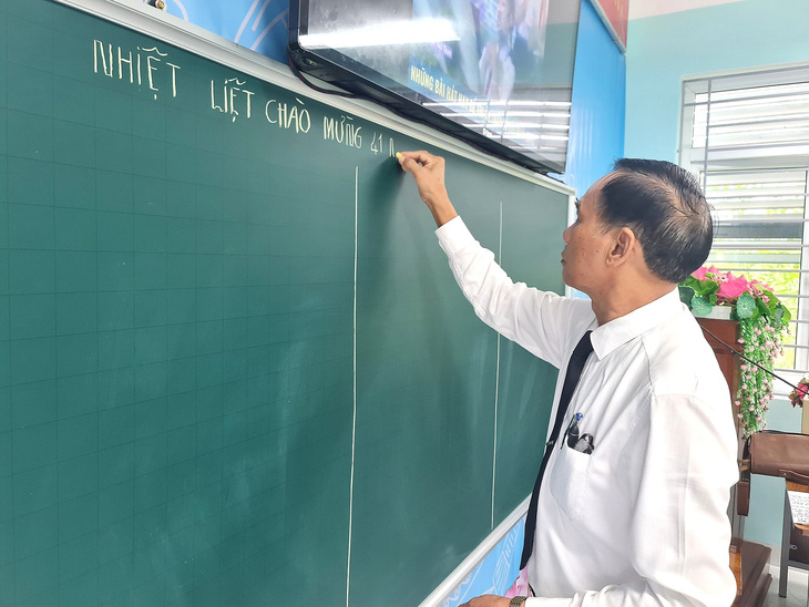 Thầy Tuệ đến trường sớm, chuẩn bị cho tiết dạy và viết dòng chữ chào mừng Ngày Nhà giáo Việt Nam - Ảnh: TRẦN MAI