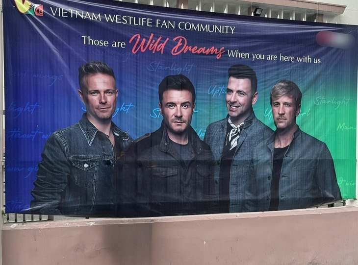 Banner in hình nhóm nhạc Westlife có logo của sàn giao dịch tiền ảo (đã làm mờ), được treo bên ngoài sân vận động Thống Nhất - Ảnh: Khán giả cung cấp trên mạng xã hội