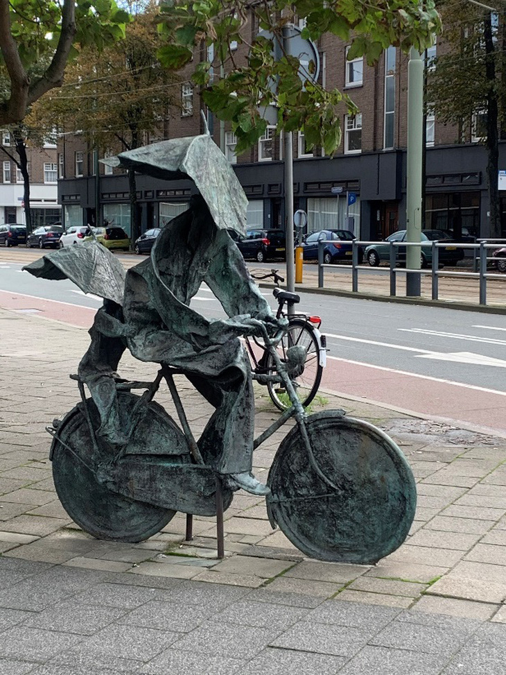Bức tượng đồng tại La Haye - Mẹ đèo con bằng xe đạp, gió mạnh gập cả 2 chiếc ô thể hiện tinh thần sống chung với những khắc nghiệt của tự nhiên của người Hà Lan - Ảnh: Tác giả Phạm Việt Anh