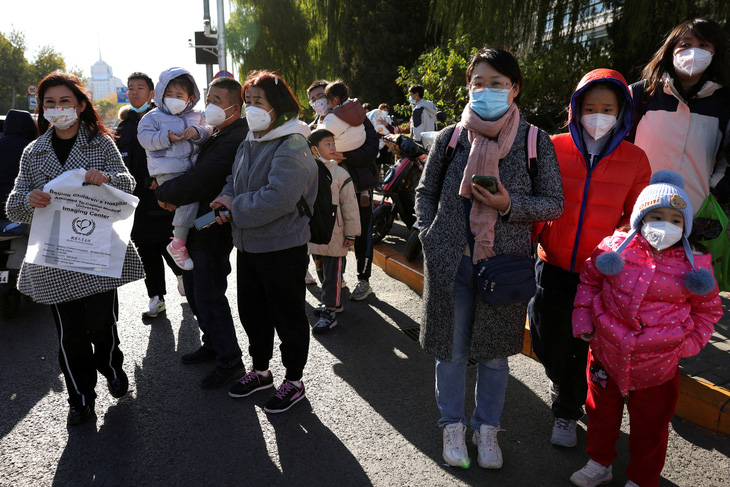 Nhiều phụ huynh cùng con nhỏ đeo khẩu trang chờ đợi tới lượt khám bên ngoài một bệnh viện nhi ở Bắc Kinh, Trung Quốc, ngày 24-11 - Ảnh: REUTERS