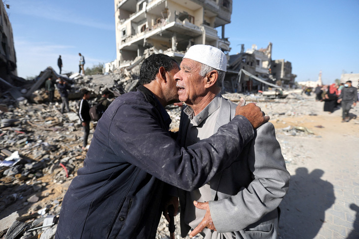 Hai người đàn ông Palestine trao nhau cái ôm trước ngôi nhà bị phá hủy do chiến tranh ở thành phố Khan Younis, sau khi lệnh ngừng bắn trong bốn ngày có hiệu lực ở Dải Gaza vào sáng 24-11 - Ảnh: Reuters