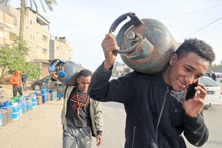 Người dân ở phía nam Dải Gaza đem bình gas rỗng đón đoàn xe chở hàng cứu trợ, nhiên liệu và khí đốtquốc tế ngày 25-11 - Ảnh: AFP