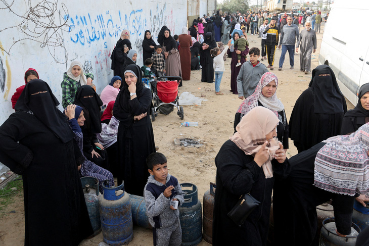 Phụ nữ và trẻ em Palestine ở Dải Gaza xếp hàng để nhận gas và một số nhu yếu phẩm - Ảnh: REUTERS