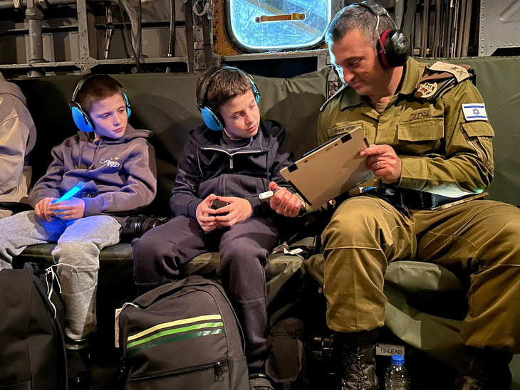 Hai anh em người Israel Tal Goldstein-Almog (9 tuổi) và Gal Goldstein-Almog (11 tuổi) ngồi cạnh binh sĩ Israel sau khi được Hamas trả tự do. Ảnh chụp tại một địa điểm không xác định và được công bố hôm 27-11 - Ảnh: REUTERS/IDF