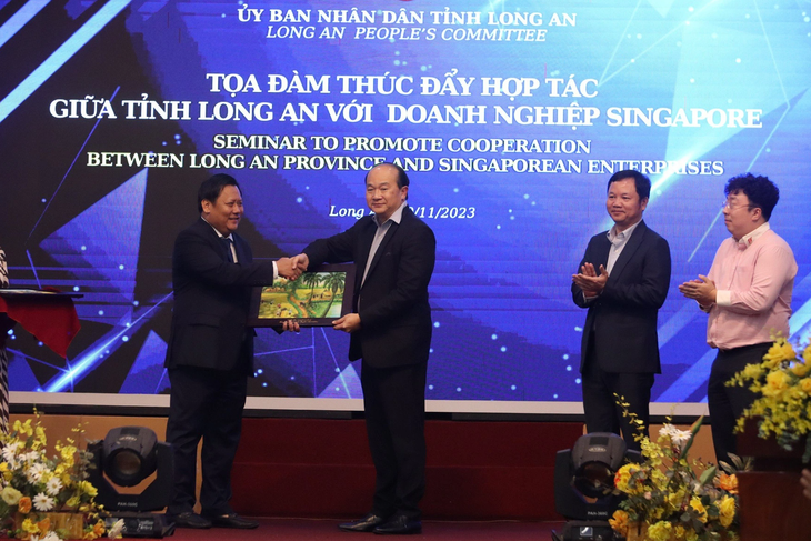 Ông Huỳnh Văn Sơn (trái) cảm ơn và tặng quà lưu niệm ông Roy Kho vì đã nối kết các doanh nghiệp Singapore đến tìm hiểu môi trường đầu tư Long An - Ảnh: SƠN LÂM