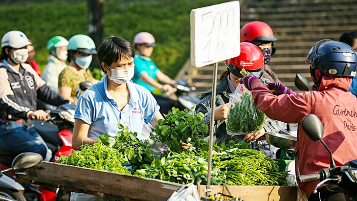 Công nhân Khu chế xuất Linh Trung 1 (TP Thủ Đức, TP.HCM) tranh thủ ghé mua rau củ giá rẻ được bày bán gần cổng công ty sau giờ làm về để tiết kiệm - Ảnh: PHƯƠNG QUYÊN