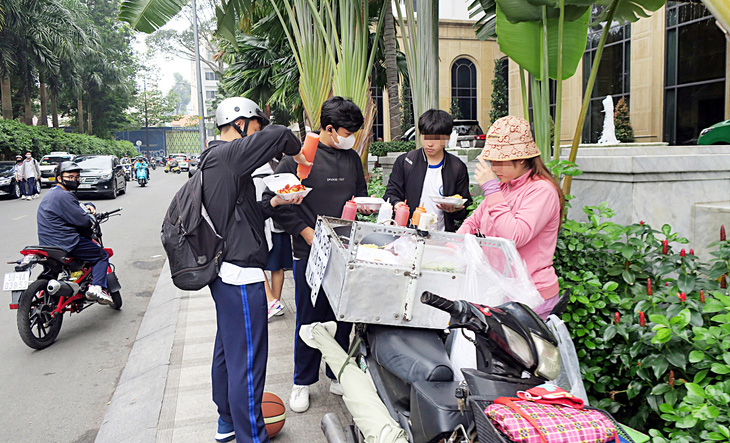 Học sinh ăn hàng rong trước cổng trường ở quận 3, TP.HCM - Ảnh: T.T.D.