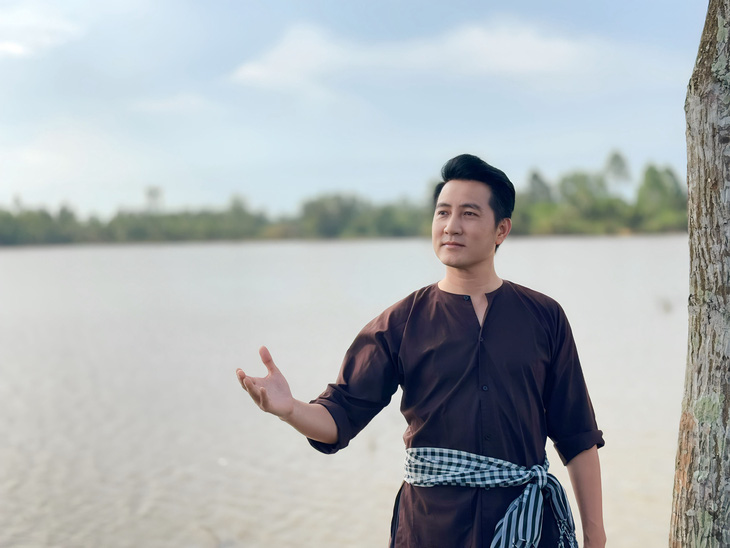 Ca sĩ Nguyễn Phi Hùng ngâm chân cả ngày trời trên cánh đồng nước nổi để quay MV Bài ca đất phương Nam - Ảnh: NVCC