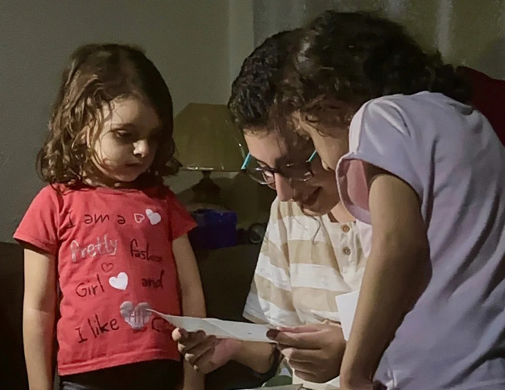 Hashem đọc tấm thiệp sinh nhật cùng người bạn Tala và Sewar - những đứa con của chủ nhà đã cho gia đình Hashem nơi trú ngụ tại Gaza - Ảnh: CNN