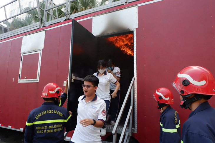 Học sinh trải nghiệm thoát hiểm từ mô hình ngôi nhà bị cháy khói mù mịt  - Ảnh: K.ANH