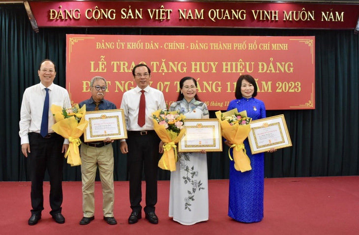 Bí thư Thành ủy TP.HCM Nguyễn Văn Nên (giữa) cùng Phó bí thư Thành ủy Nguyễn Hồ Hải (bìa trái) trao huy hiệu 30 năm tuổi Đảng - Ảnh: CẨM NƯƠNG