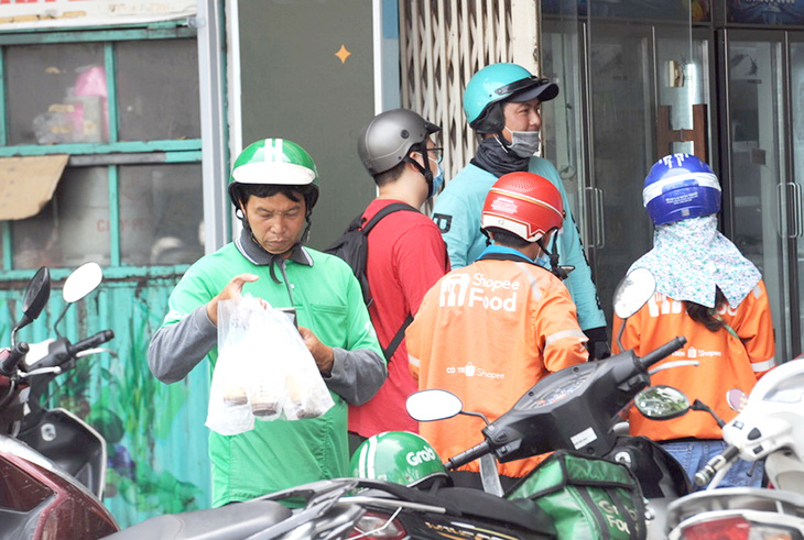 Tài xế Grab nhận giao đồ ăn nhanh cho khách trên đường Nguyễn Đình Chiểu, quận 3, TP.HCM - Ảnh: HẢI QUỲNH