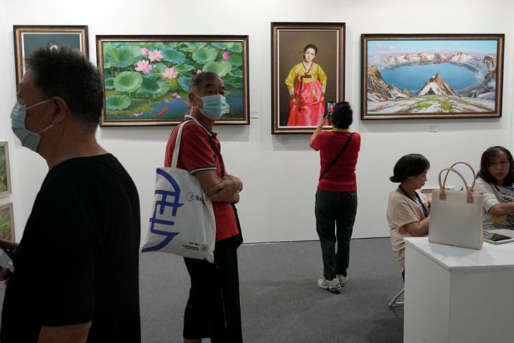 Khách tham quan triển lãm nghệ thuật Bắc Kinh hồi tháng 9 đi ngang qua một gian trưng bày các bức tranh vẽ về Triều Tiên của phòng trưng bày The Paintings Say Arirang - Ảnh: YONHAP/AP